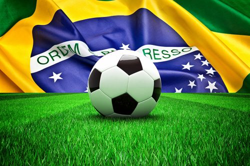 soccer ball on grass and brazil flag